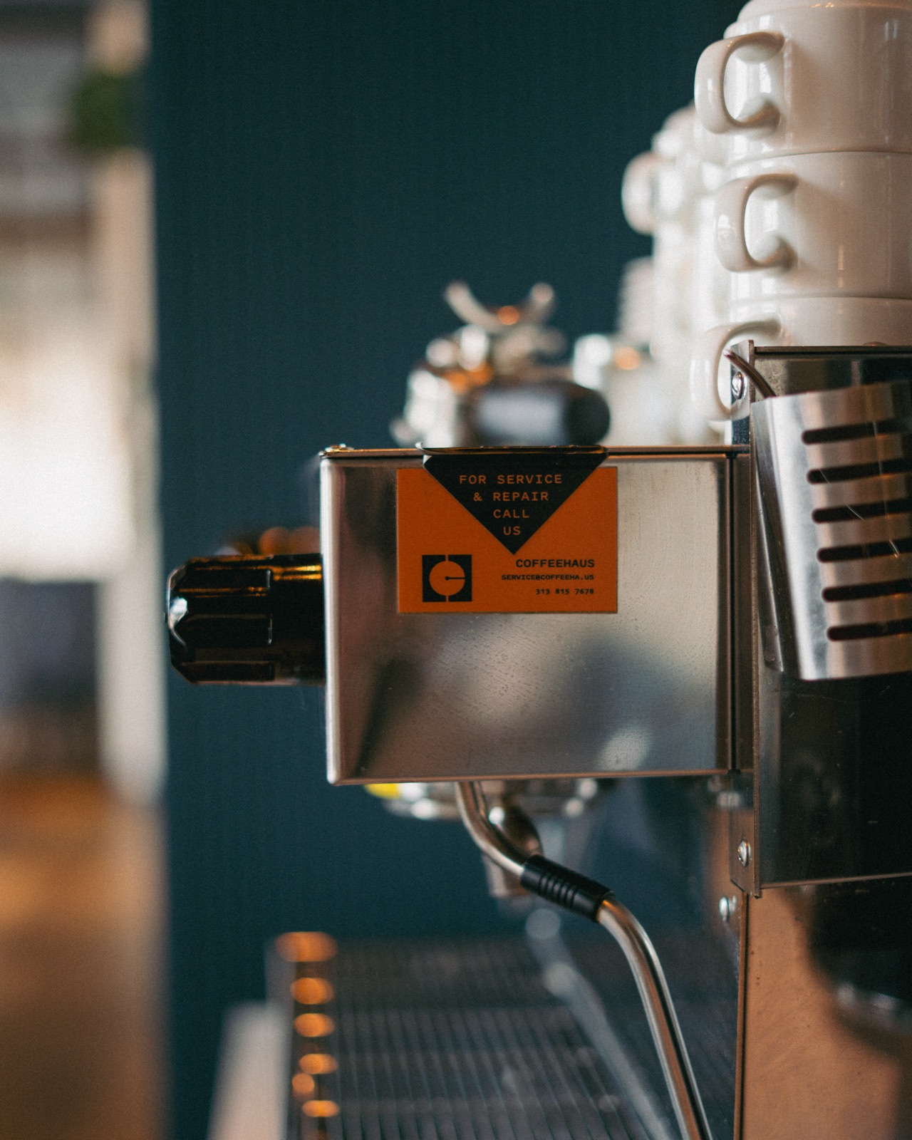Close-up of the Coffeehaus For Service and Repair sticker on the front of the Godfrey Hotel's La Marzocco