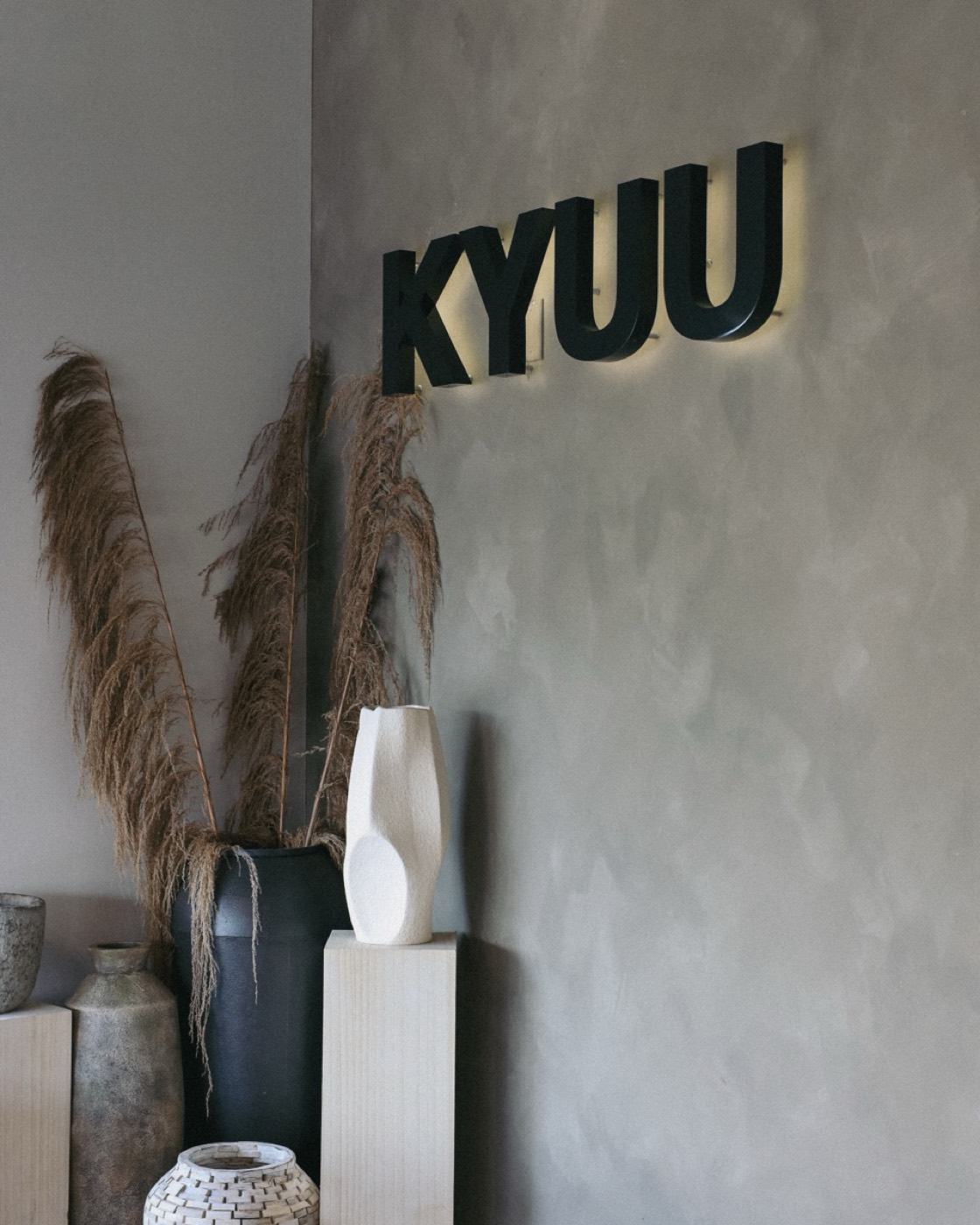 Kyuu Cafe interior with black wall-mounted signage, pampas grass, and ceramic vases