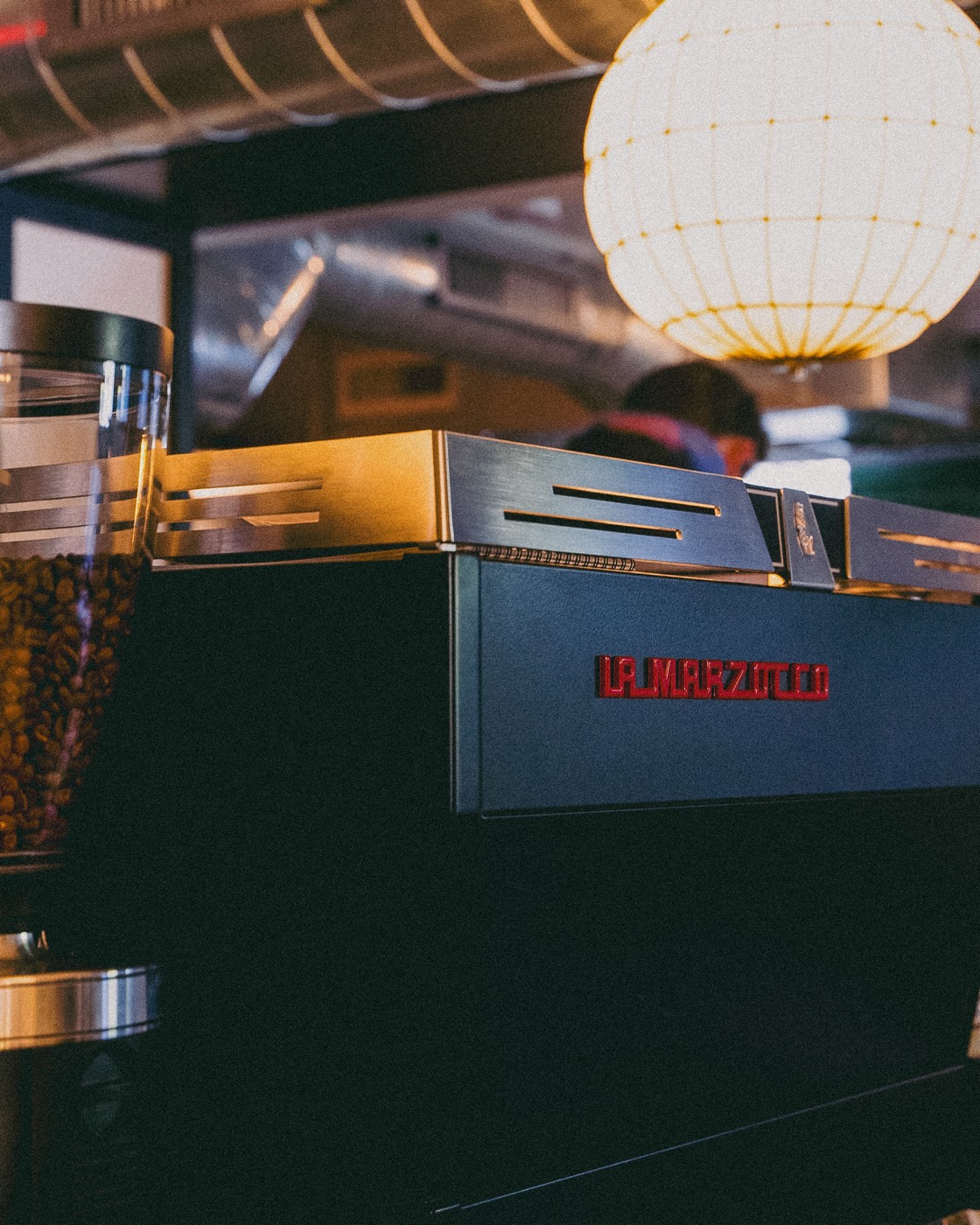 La Marzocco espresso machine and grinder hopper under a paper lantern