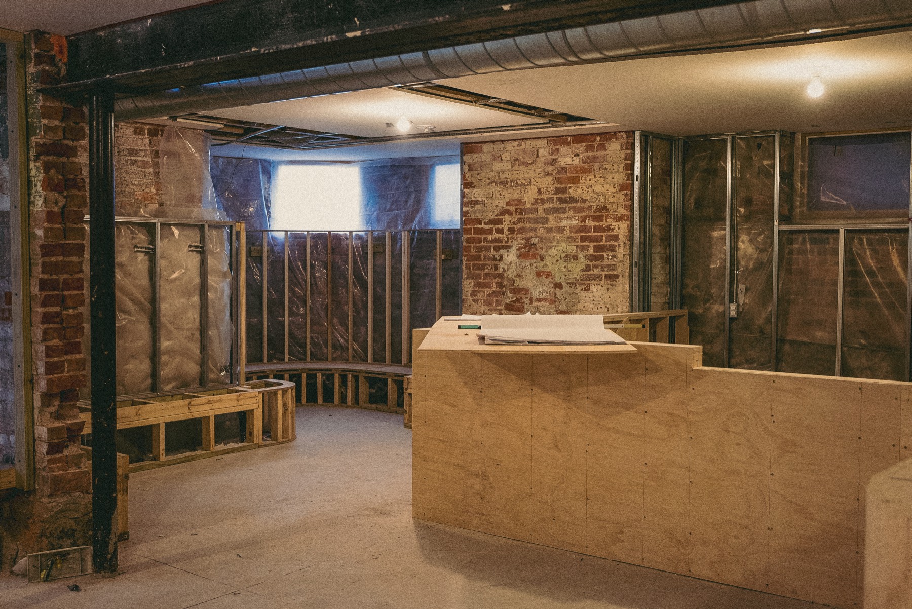 Cafe Sous Terre mid build-out: plywood bar, exposed brick, drawings on the counter